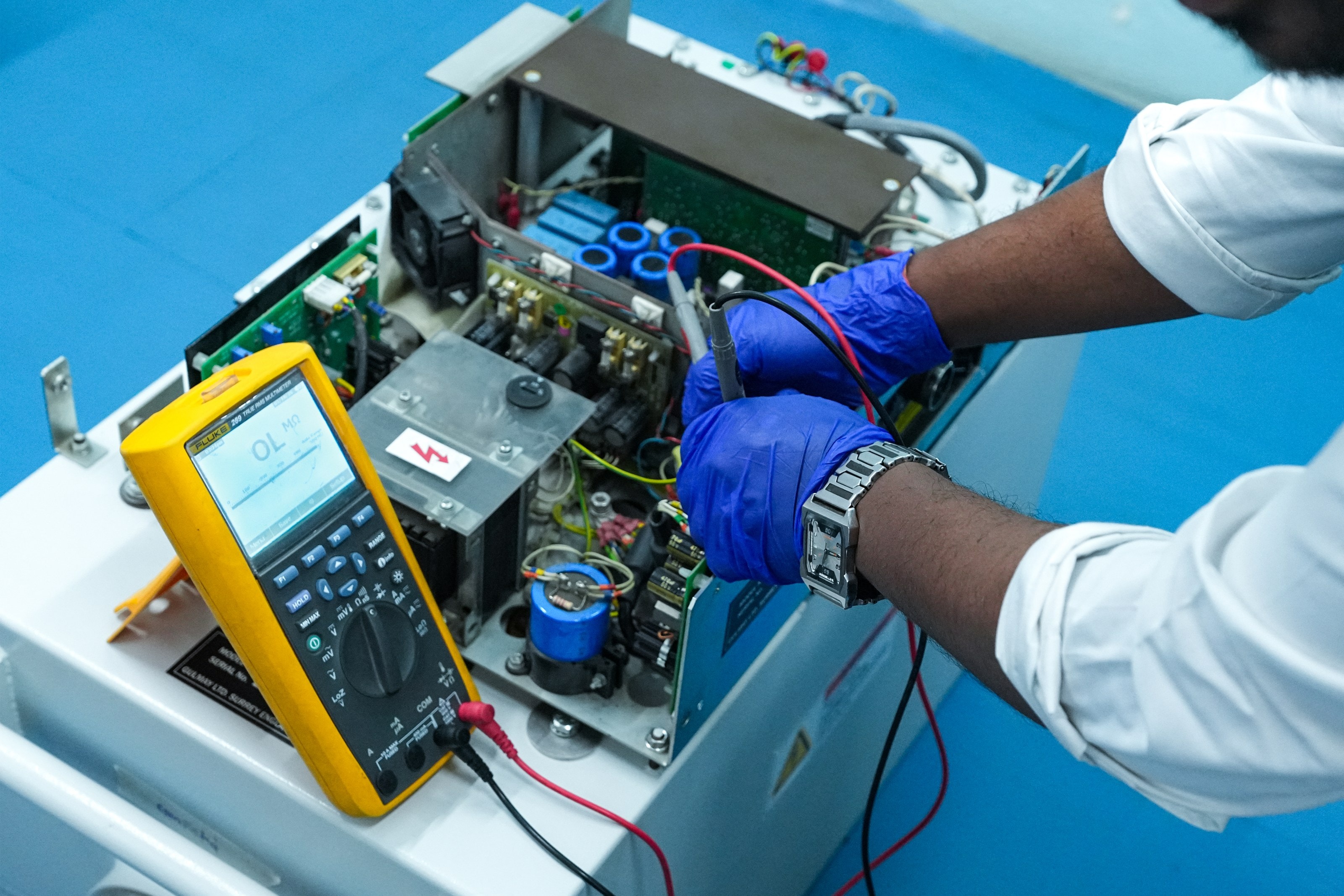 MQS engineer performing electrical testing on a system's control electronics with a digital multimeter